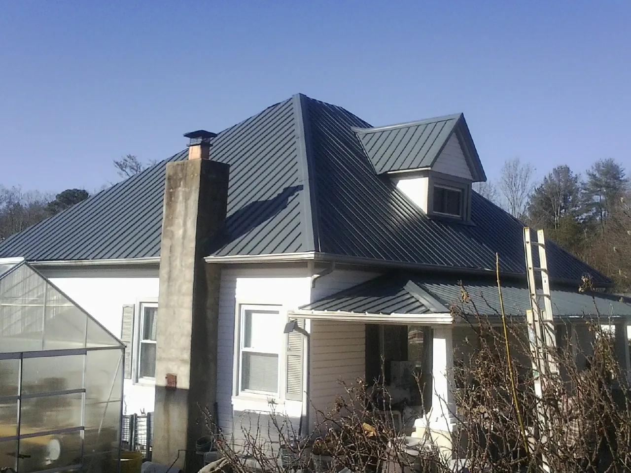 Dark blue standing seam metal roof on a white farmhouse with dormer — Slate & Tile Roof Repair by Roofing Brothers in Unadilla