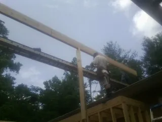 Carpenter setting a ridge beam over a new addition frame — Ice Dam Removal by Roofing Brothers in Unadilla