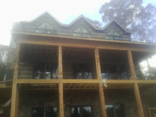 Dormers and porch framing on a large log home under construction — Roof Coating work by our crew in Unadilla