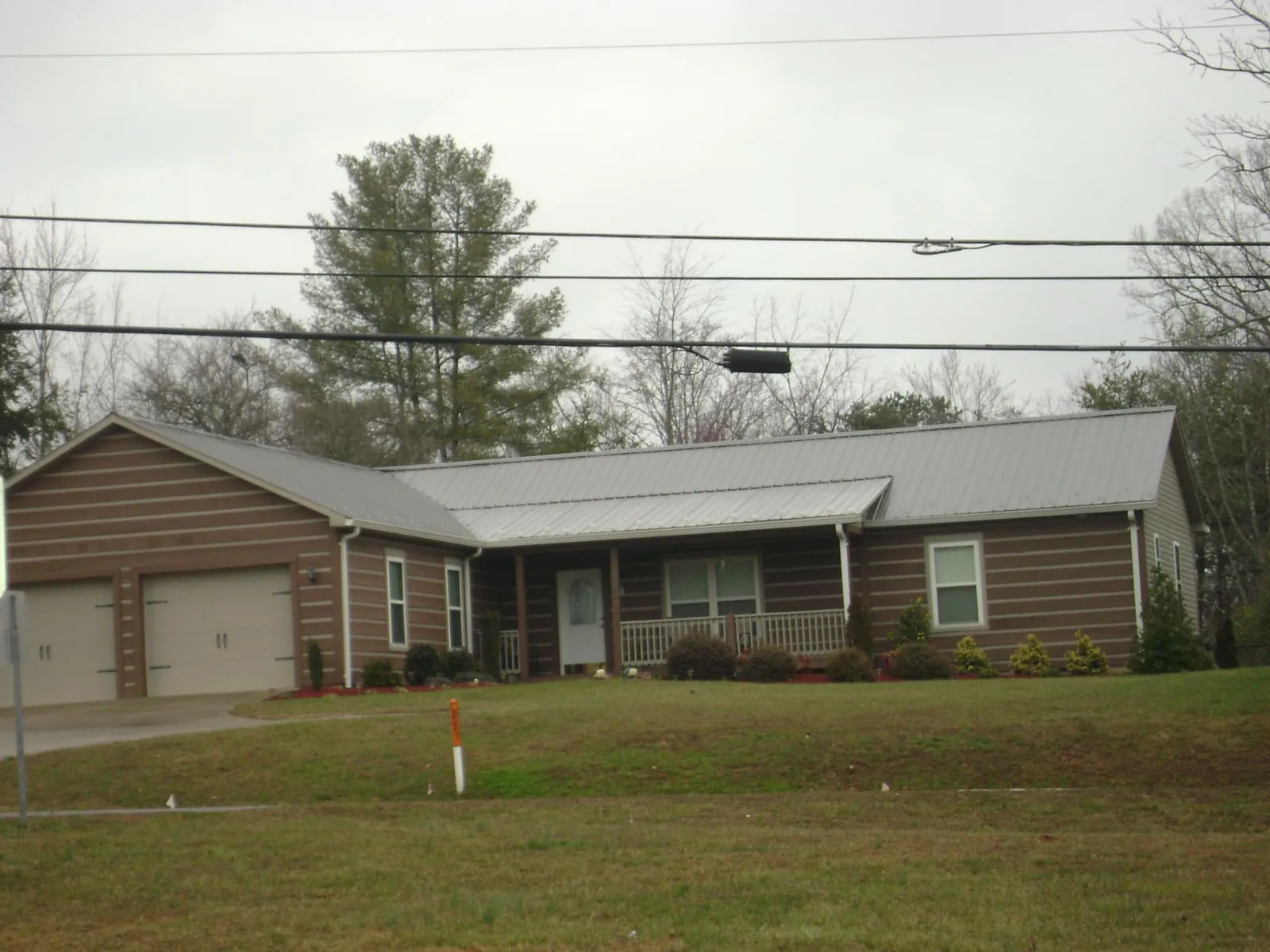 Gray metal roof on a log sided ranch home with a front porch in Unadilla