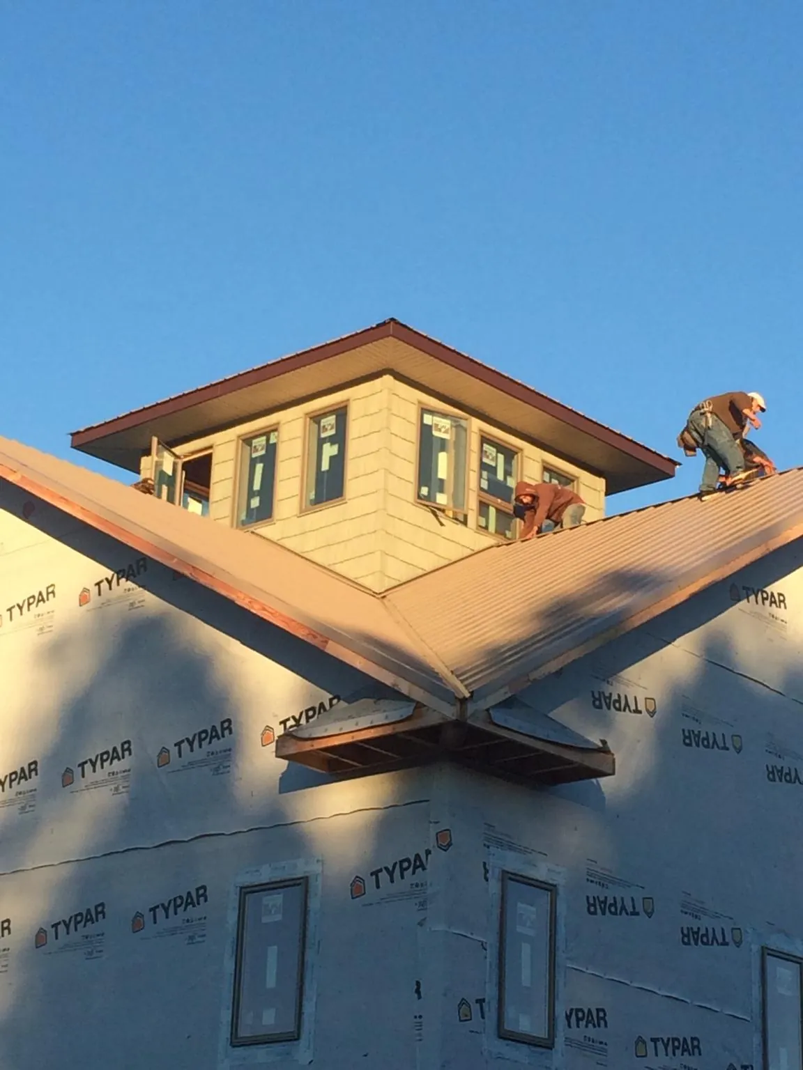 Roofers working around a rooftop cupola on a new metal roof at sunset — Roof Waterproofing in Unadilla by Roofing Brothers